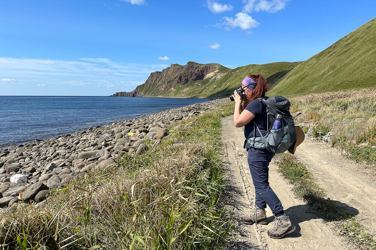 A women taking a photo while standing on a trail near a beach on Rebun Island, Hokkaido.